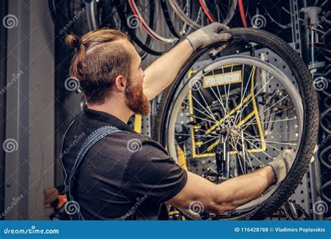 Mechanic Repairing Bicycle Wheel Tire In A Workshop Stock Photo