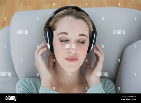 Pretty Natural Woman Listening With Headphones To Music Lying On Couch