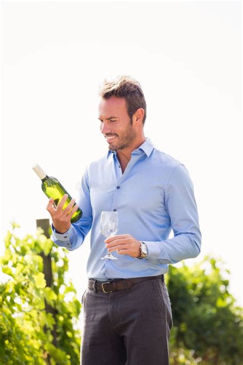 Smiling Man Holding Wine Bottle And Glass Against Sky Stock Photo