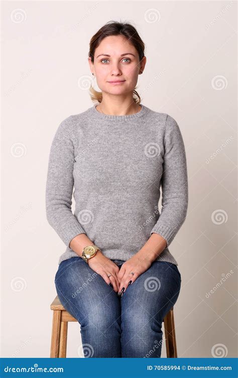 Portrait Of Beautiful Young Woman Sitting On Chair In Studio Stock