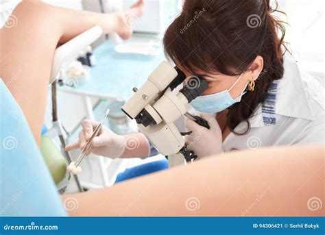 professional gynecologist examining female patient on gynecological chair holding forceps stock