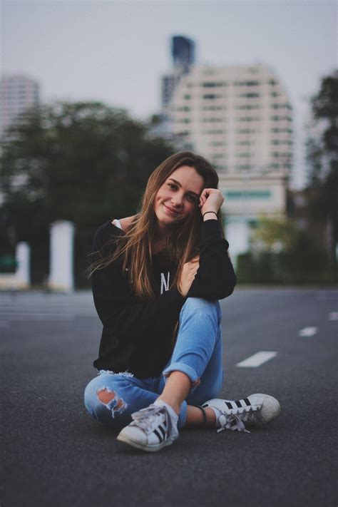 Woman Smiling While Sitting On Road With Hand Resting On Top Of Her