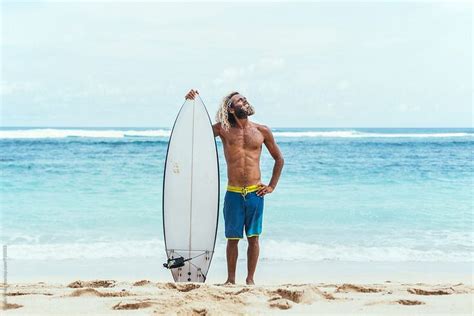 Portrait Of A Handsome Man Holding His Surfboard On The Beautiful