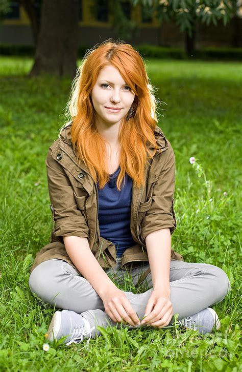 Romantic Portrait Of A Young Redhead Girl Sitting In The Park