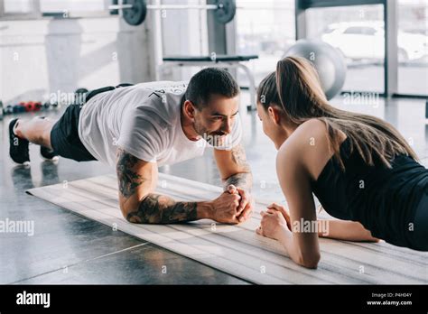 Male Personal Trainer And Sportswoman Doing Plank At Gym Stock Photo