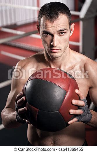 Muscular Man Holding Fitness Ball In Front Of Chest Expressing