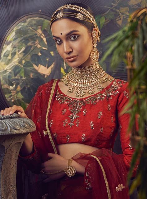 A Woman Wearing A Red Outfit With Gold Jewelry