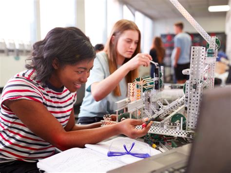 Two Female College Students Building Machine In Science Robotics Or