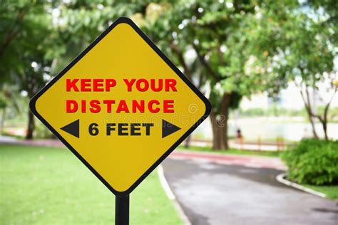 Keep Your Distance And 6 Feet Word On Yellow Sign At Park Background