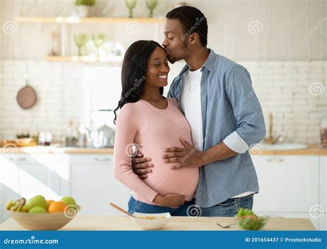 Maternity And Healthy Eating Concept Caring Black Husband Kissing His Pregnant Wife In Kitchen