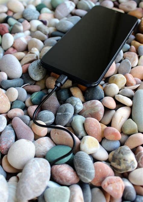 Smartphone With Screen Off Charging Via Cable Disappearing Into Sea