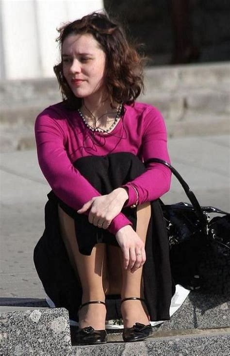 Симпатичная женщина сидя на улице в телесных колготках под юбкой 1