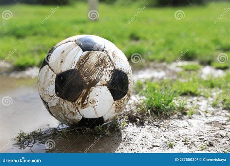 Dirty Soccer Ball On Green Grass Near Puddle Outdoors Space For Text