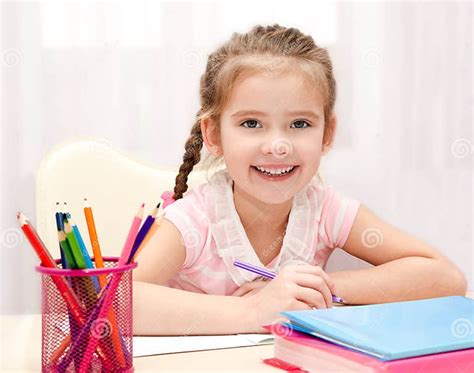 Cute Smiling Little Girl Is Writing At The Desk Stock Image Image Of