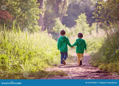 Two Boys Walking Through A Mud Puddle Royalty Free Stock Photography