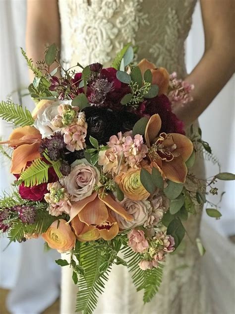A list of rose wedding bouquets that highlight unexpected ways to include the classic wedding flower. Bridal bouquet with burgundy peonies and ranunculus, peach ...