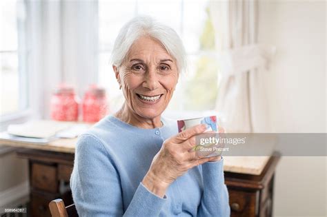 Portrait Of Smiling Senior Woman At Home Holding Cup Photo Getty Images