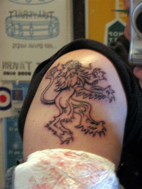 A Man With A Lion Tattoo On His Arm Holding A Camera And Taking A Photo