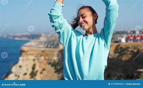 Portrait Of Happy Young Woman Standing On Cliff Edge Against Amazing Seascape And Sky Hair