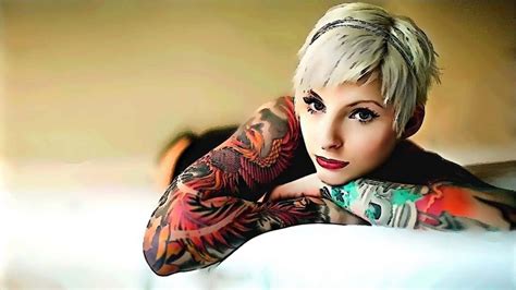 Download A Woman With Tattoos Laying On A Bed