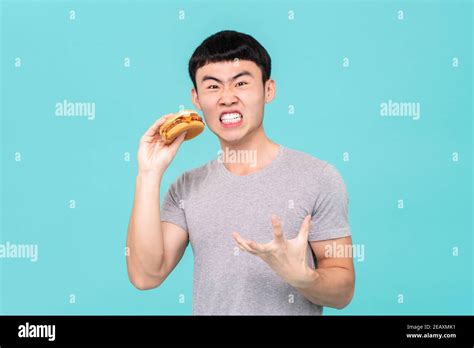 Dieting Hungry Asian Man Having Funny Facial Expression While Holding