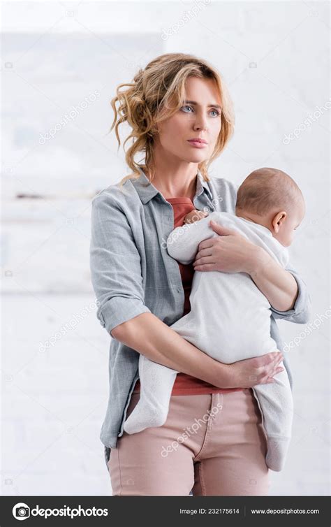 Tired Mother Holding Cute Infant Child Looking Away Home Stock Photo By