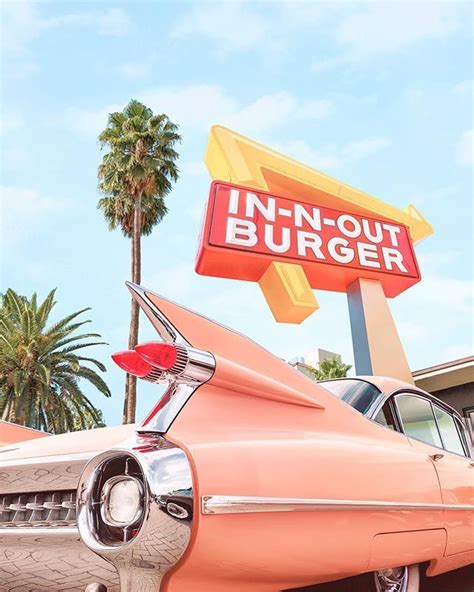 An Old Pink Car Is Parked In Front Of A Neon Out Burger Sign And Palm