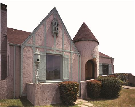 a pink and green house with two towers on the top of it's roof