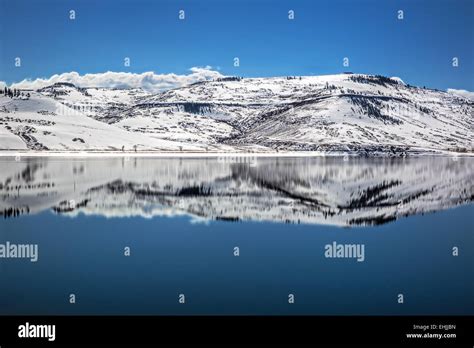 Reflection Of Snowy Mountains Surrounding Partial Frozen Blue Mesa