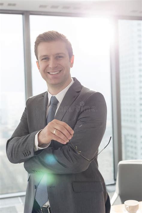 Portrait Of Smiling Businessman Standing With Eyeglasses At Office