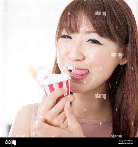 Portrait Of Attractive Asian Girl Eating Cupcake And Licking On Her