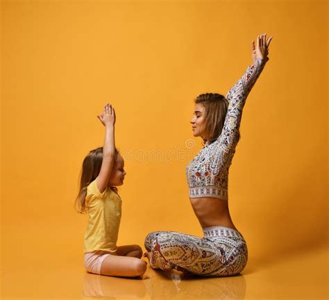 Young Mother And Daughter Doing Yoga Exercises Together In A Fitness