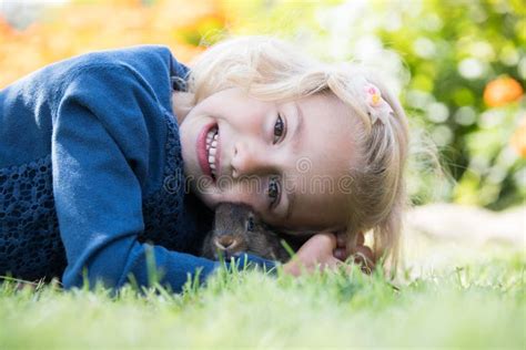 Happy Laughing Little Girl Playing With A Baby Rabbit Stock Photo