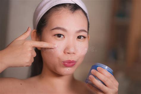 Domestic Lifestyle Portrait Of Young Beautiful And Happy Asian Korean Woman Applying Facial