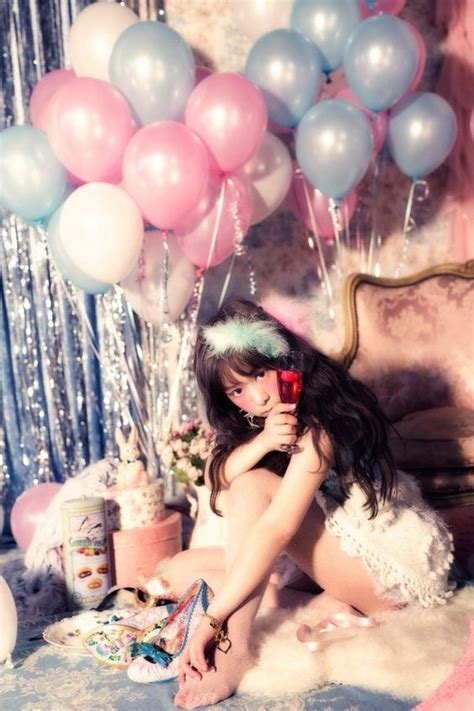 A Woman Sitting On The Floor With Balloons And Confetti In Front Of Her