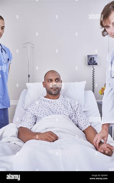 Doctors Taking Pulse Of Patient Lying In Hospital Bed Stock Photo Alamy