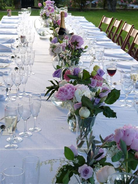 A Long Table Is Set Up With Wine Glasses And Flowers In Vases On It