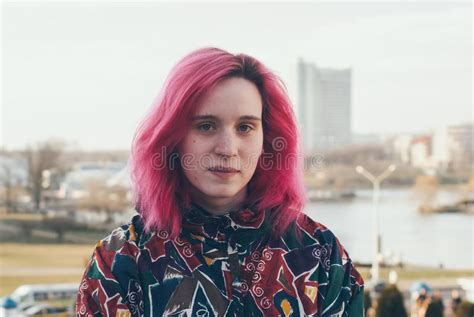 Modern Young Girl With Pink Hair Stands On The Background Of The Urban