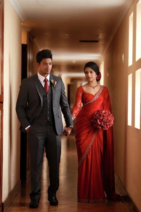 A Man And Woman Dressed In Formal Wear Walking Down A Hallway Holding