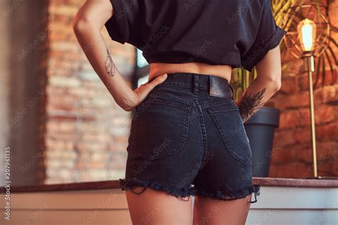 Cropped Shot Of A Slim Sexy Girl Showing Her Butt In Black Shorts And T Shirt Posing In Studio