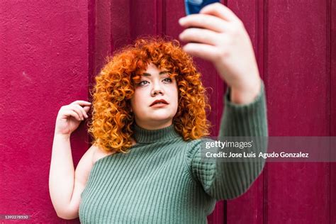 a chubby redhead girl taking a photo with her cell phone portrait of a chubby redhead woman