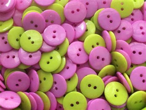 A Pile Of Pink And Green Buttons Sitting On Top Of Each Other