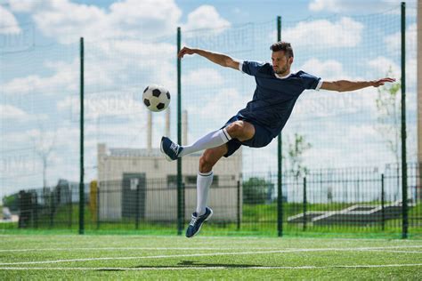 Athletic Soccer Player Kicking Ball On Soccer Pitch Stock Photo