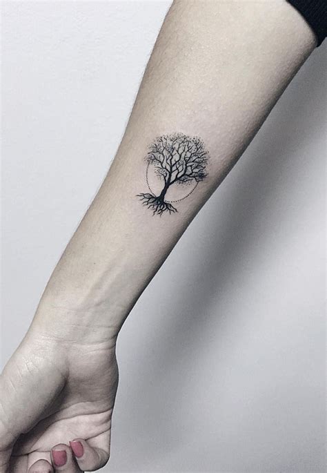 a small tree tattoo on the left inner forearm and wrist is shown in black ink