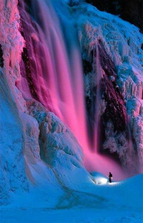 A Man Standing In The Snow Next To A Waterfall