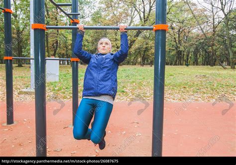 Sporty Girl Doing Pull Ups Exercise At Outdoor Gym Lizenzfreies Bild