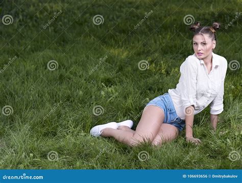 Молодая красивая женщина сидя на ждать лужайки Стоковое Фото изображение насчитывающей одно