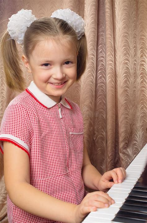 Portrait Of Little Girl In White Dress Playing Piano Stock Photo