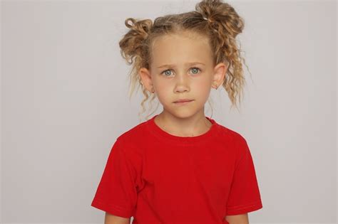 una chica rubia con una camiseta roja y jeans con coletas muestra emociones foto premium