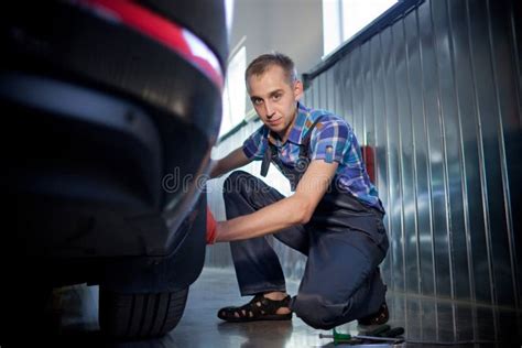 Element Of Auto Mechanic Working Underneath A Lifted Car Stock Photo